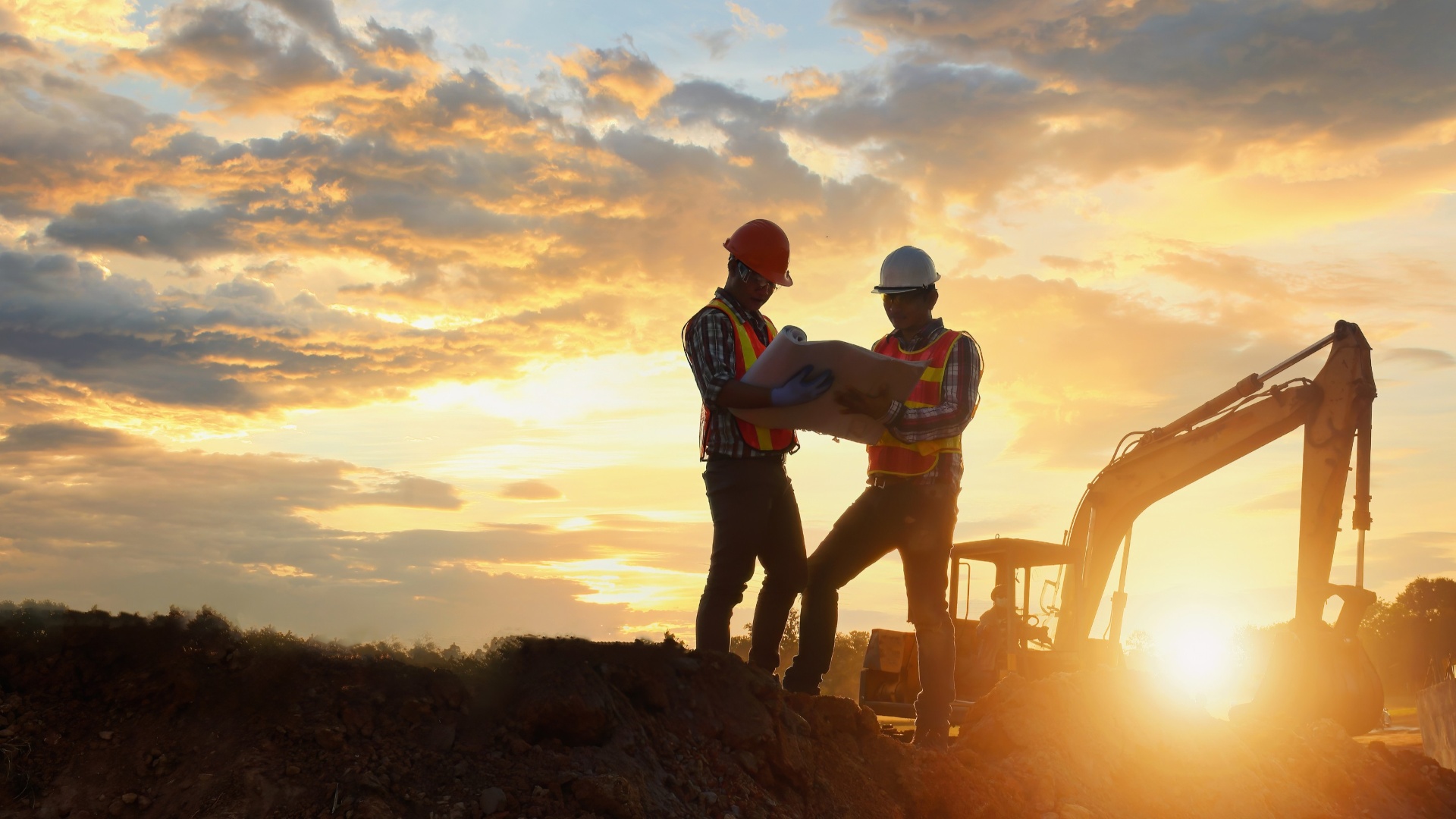 construction engineers onsite with a tractor in background 
