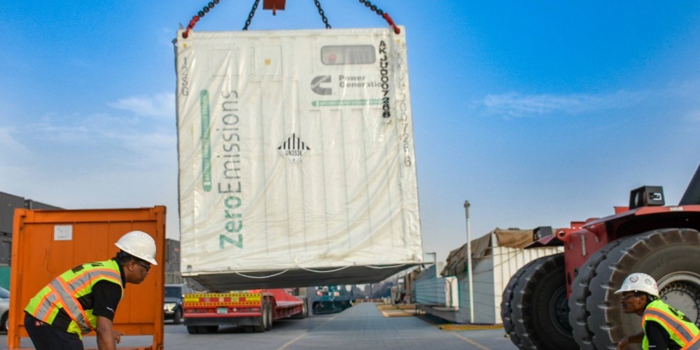 Battery Energy Storage System being lifted with a crane with 2 people helping.
