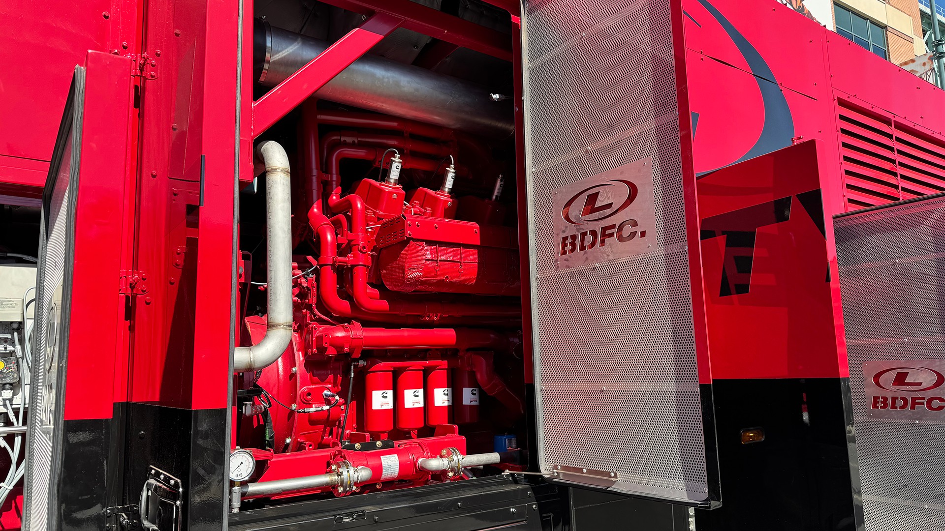 Red industrial engine inside a power generation enclosure with access doors open