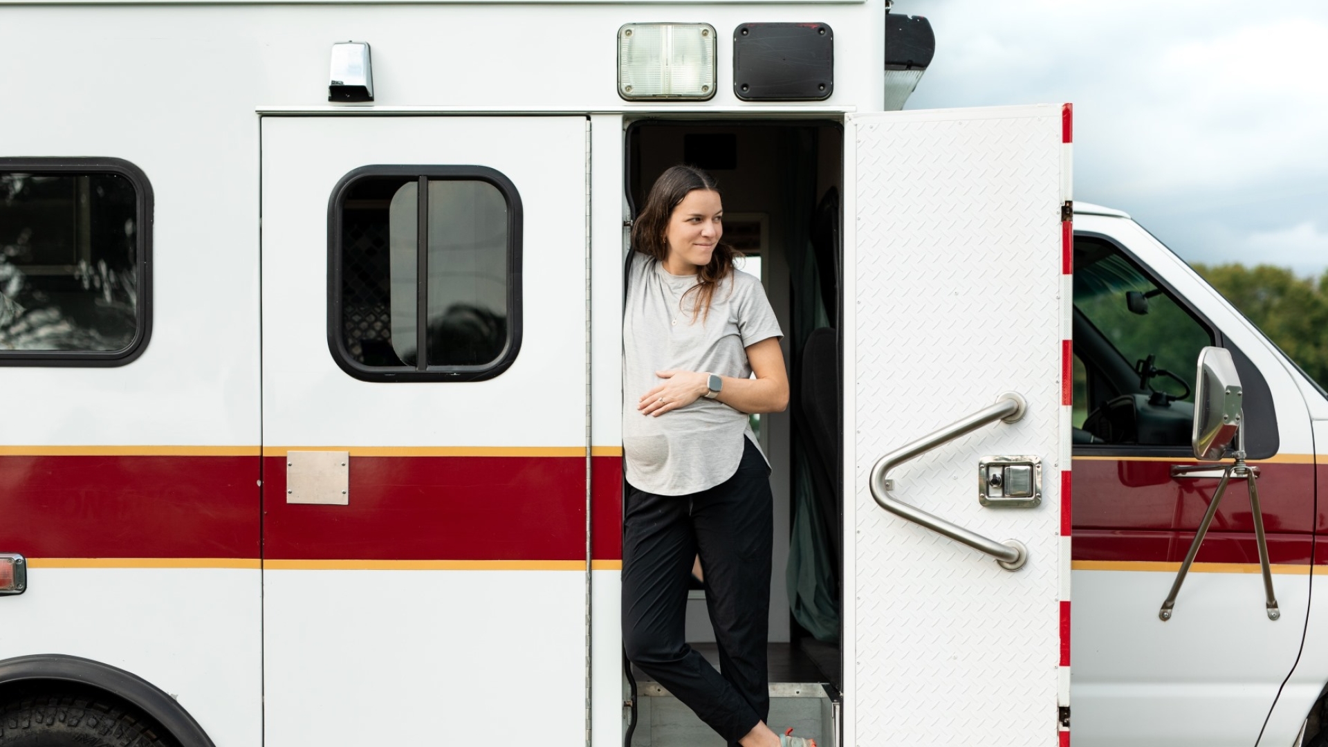 pregnant woman standing in doorway of camper van
