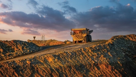 Haul truck on top of a slope with the sun setting in the background