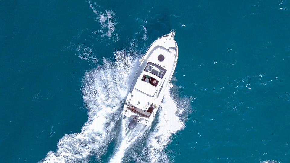 Overhead view of a motorboat moving across clear blue water