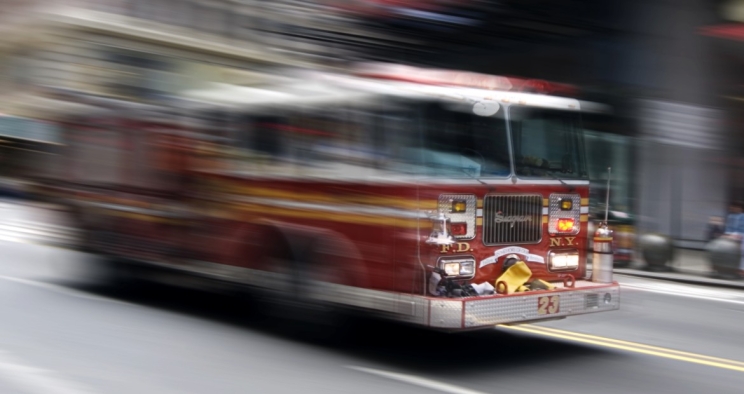 Red fire truck driving at speed on a city street
