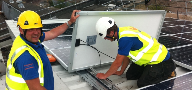 workers wearing safety equipment install solar panels