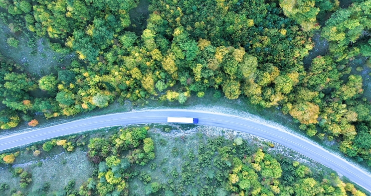 A semi truck driving on a winding road through the forest