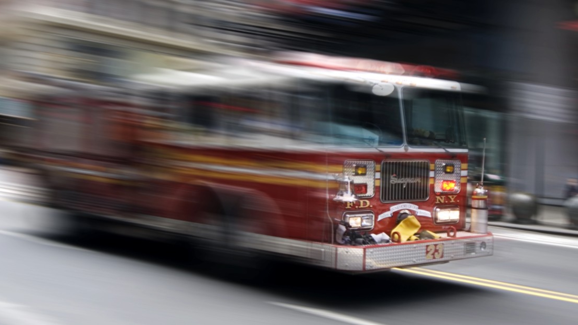 Red fire truck driving at speed on a city street
