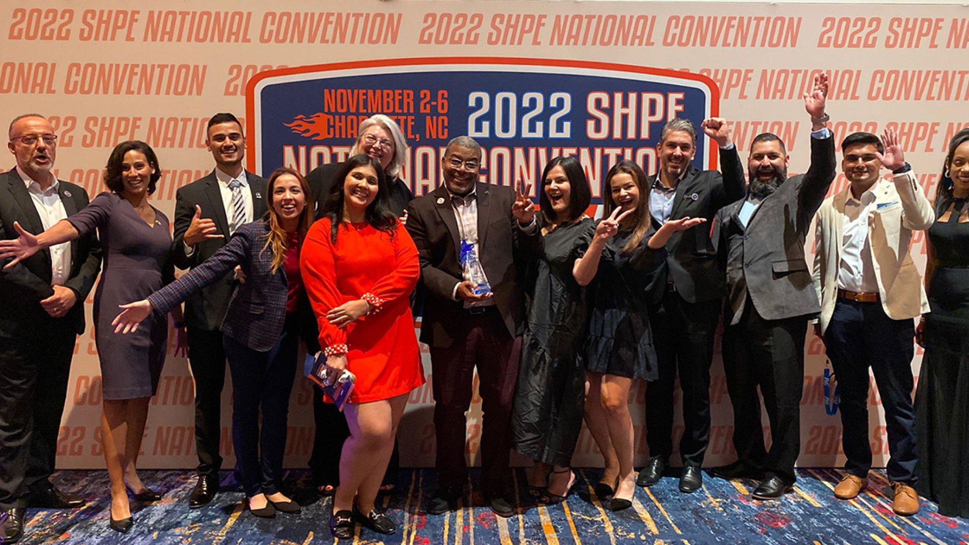 Employees in front of SHPE awards banner