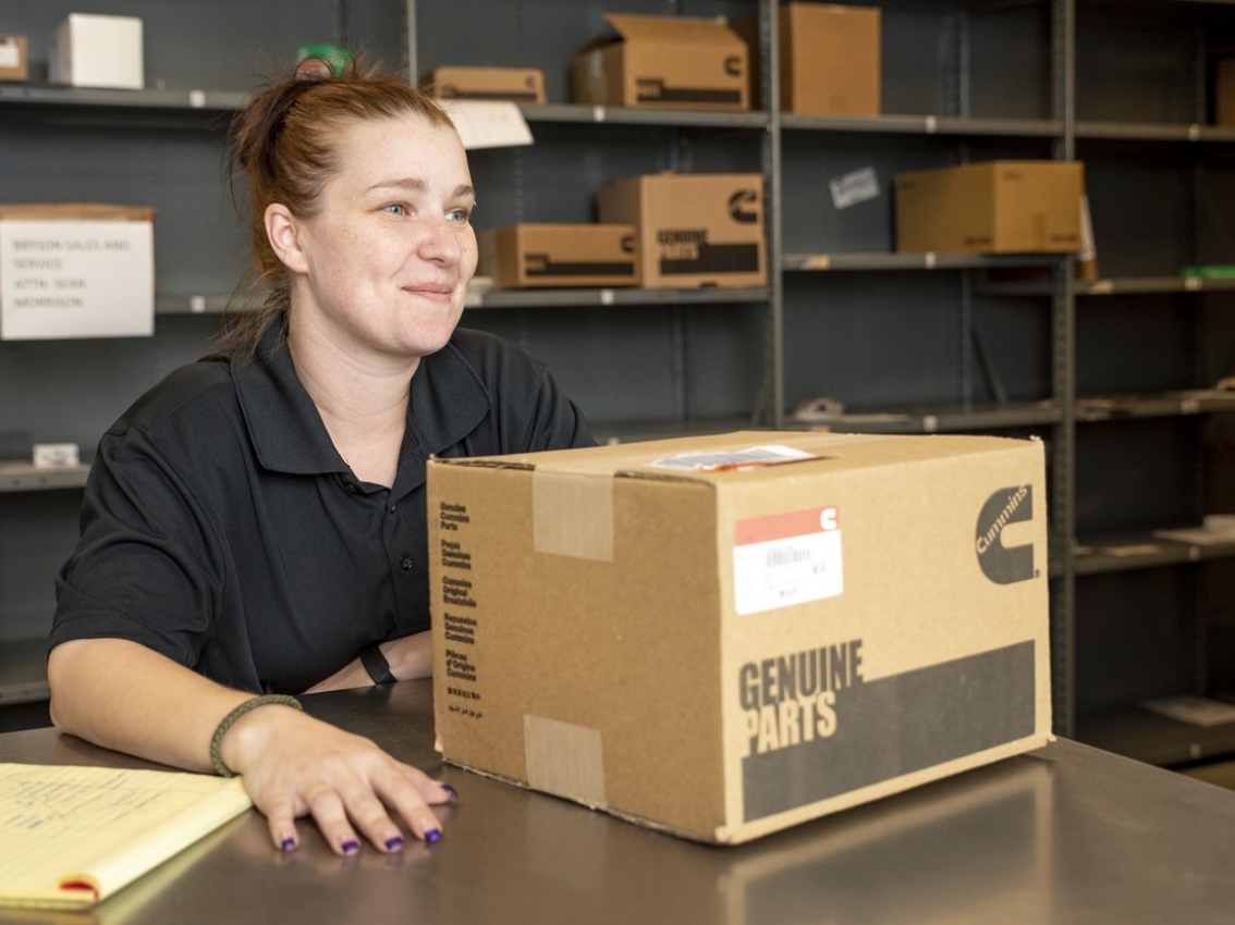 Cummins worker with a box of Cummins Genuine parts on a desk